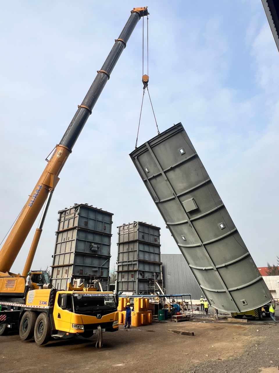 Yellow crane lifting a large curved metal structural panel